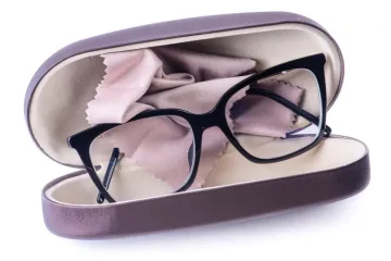 A pair of black-framed glasses resting in an open hard case with a cleaning cloth.