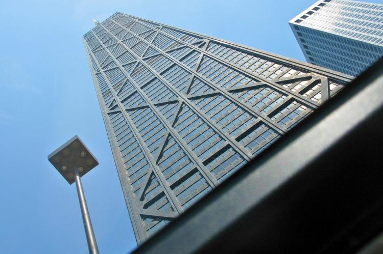 Upward view of the John Hancock Center with its X-braced exterior against a clear blue sky.