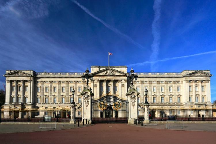 Front view of Buckingham Palace in London with a clear blue sky and the Union Jack flag flying.