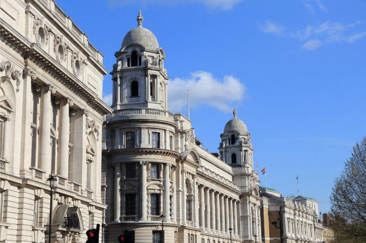 Historic Whitehall buildings in London showcasing classical architecture with columns and domes against a bright blue sky.