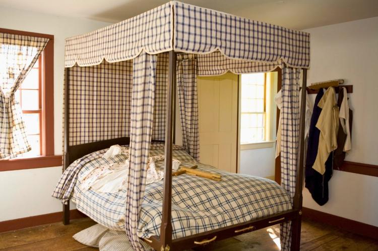 Traditional American Colonial bedroom with a four-poster canopy bed and plaid drapes.