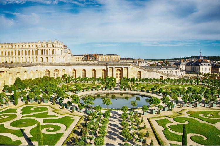 The gardens of Versailles with geometric hedges, fountains, and an orangerie.