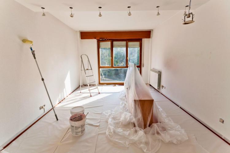 Room prepared for painting with protective coverings, paint supplies, and a stepladder.