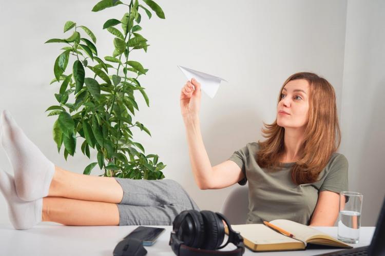 A young woman procrastinating by flying paper planes.