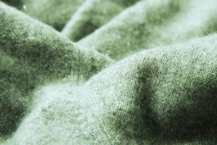 Detail of a cashmere jumper in a soft green color.
