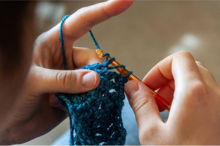 Hands of a woman knitting a simple crochet band.