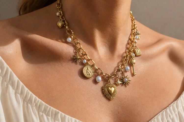 Chunky gold charm necklace with dangling hearts, coins, stars, keys, pearls, and vintage-inspired pendants.