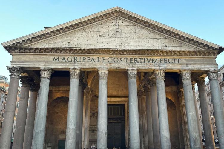 Front of the Pantheon in Rome with ancient stone columns, triangular pediment and Latin inscription.