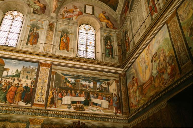 Elaborate Renaissance frescoes covering the walls and vaulted ceiling of the Sistine Chapel in Vatican City.