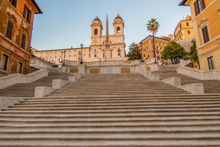 Wide stone staircase of the Spanish Steps leading up to the Trinità dei Monti church in Rome.
