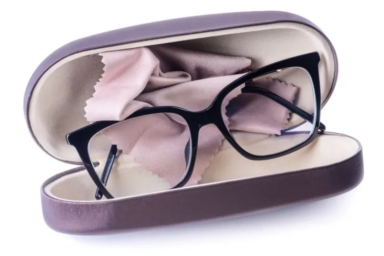 A pair of black-framed glasses resting in an open hard case with a cleaning cloth.