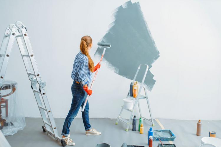 Female painter with roller painting a wall.